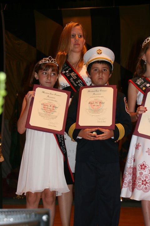 Ms. Fire Prevention Solveig Petersen, Jr Miss Victoria Pilpel and Little Fire Chief Bryan Pilpel pose on stage  during the competetion.